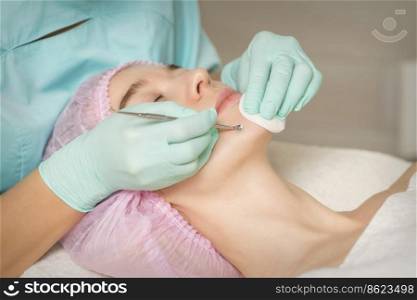 Facial cleansing. Blackhead Removal Tool. Beautician removing blackhead and acne on female chin in a beauty salon. Beautician removing blackhead and acne