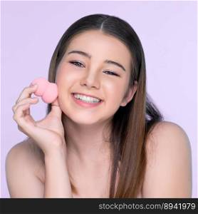 Facial cosmetic makeup concept. Portrait of young charming girl applying dry powder foundation. Beautiful girl smiling with perfect skin putting cosmetic makeup on her face.. Portrait of young charming girl applying dry powder foundation on her face.