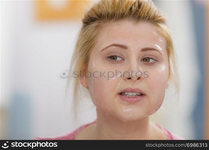 Facial dry skin and body care, complexion treatment at home concept. Young woman having gel peel off mask on her face.. Young woman having gel mask on face