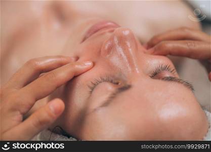 Facial massage beauty treatment. Close-up of a young woman’s face lying on back, getting face lifting massage, pinch and roll technique. . Facial Lift Massage, Pinch and Roll Technique