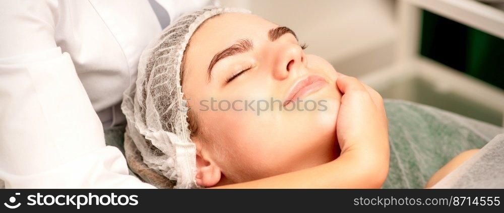 Facial massage. Hands of a masseur massaging neck of a young caucasian woman in a spa salon, the concept of health massage. Facial massage. Hands of a masseur massaging neck of a young caucasian woman in a spa salon, the concept of health massage.