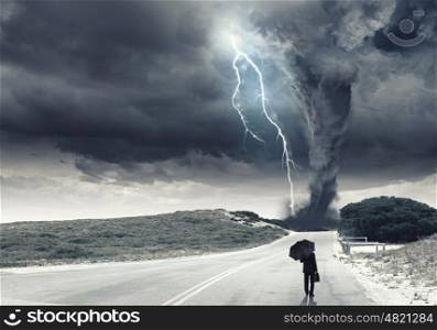 Facing challenges. Back view of businessman with umbrella and suitcase facing tornado