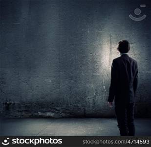Facing challenges. Rear view of businessman looking at blank cement wall