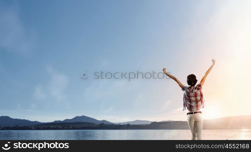 Facing new day. Rear view of girl with hands up facing sunrise