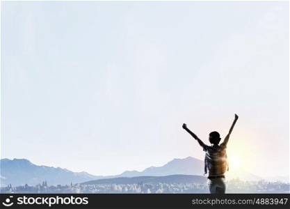 Facing new day. Rear view of girl with hands up facing sunrise