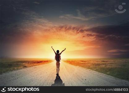 Facing new day. Rear view of girl with hands up facing sunrise