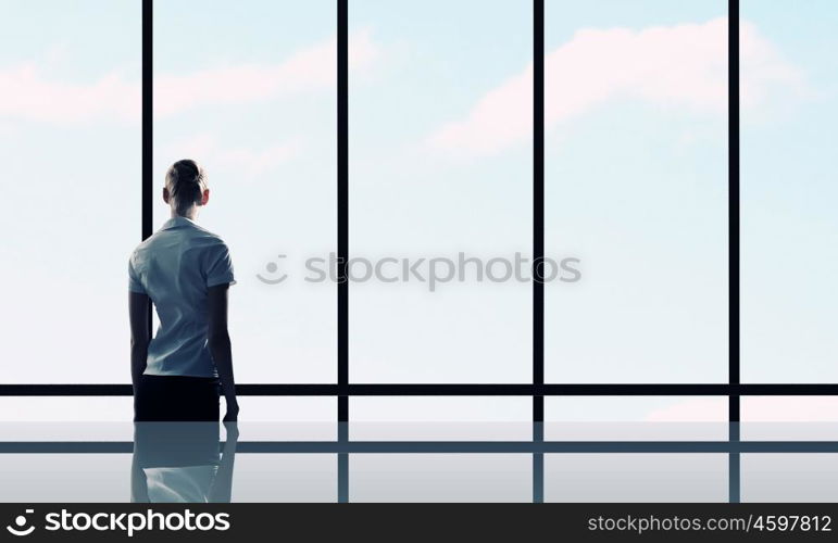 Facing next successful day. Back view of businesswoman looking in office window