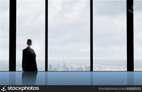 Facing next successful day. Back view of businesswoman looking in office window