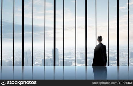 Facing next successful day. Back view of businesswoman looking in office window