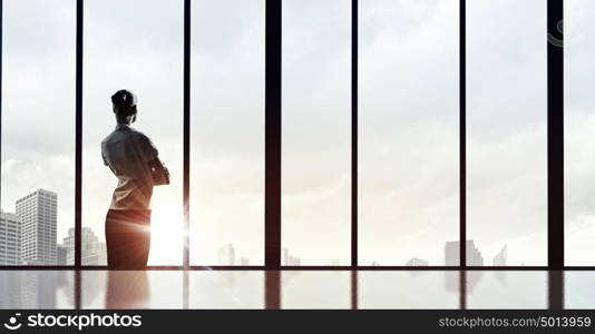 Facing next successful day. Back view of businesswoman looking on sunrise in office window