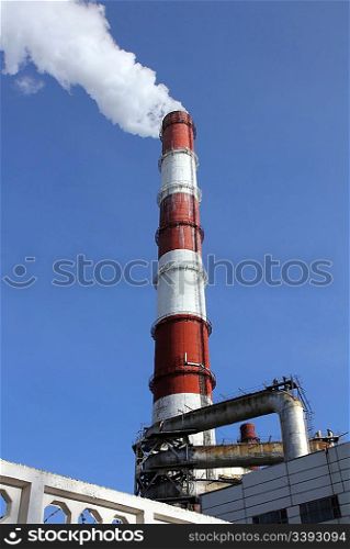 factory chimneys with smoke under blue sky