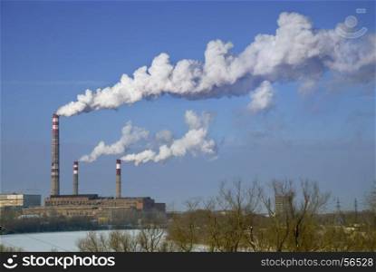 factory chimneys with white smoke against a blue sky