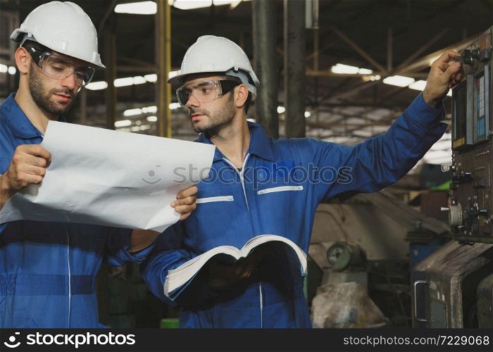 Factory Engineer or mechanical worker with white safety helmet checking on production in a factory. Industrial,Warehouse Heavy Mechanic, Engineering Concept.