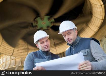 factory engineers studying a project blueprint