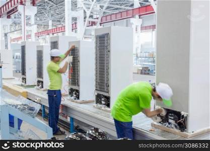 factory floor for production and assembly of household refrigerators on the conveyor belt. factory workers collect refrigerators on the conveyor belt. Plant for the production of refrigerators