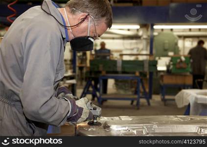 factory floor worker using a angle grinder on metal surface