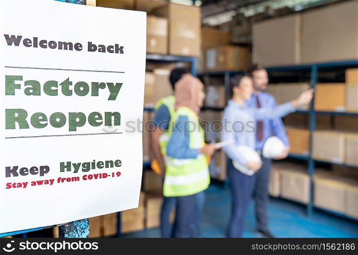 Factory reopen signage with warehouse manager and worker meeting in background after city lockdown from COVID-19 coronavirus pandemic in warehouse distribution center environment.