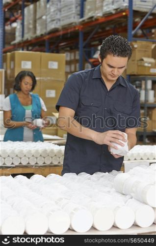 Factory Worker Checking Goods On Production Line
