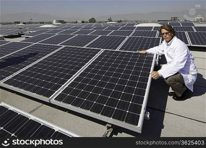 Factory worker sitting besides solar panels
