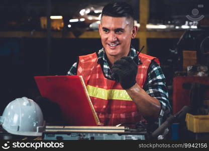 Factory worker talking on portable radio while inspecting machinery parts . Industrial and engineering team communication concept .