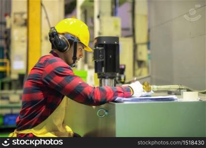 Factory worker with plaid shirt, helmet, safety glasses write production result on paper to reprort inspector and factory manager. Manufacturing industry