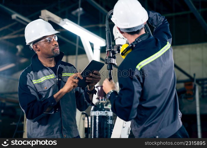 Factory workers working with adept robotic arm in a workshop . Industry robot programming software for automated manufacturing technology .. Factory workers working with adept robotic arm in a workshop