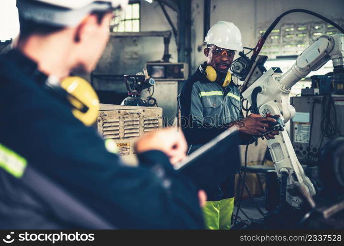 Factory workers working with adept robotic arm in a workshop . Industry robot programming software for automated manufacturing technology .. Factory workers working with adept robotic arm in a workshop