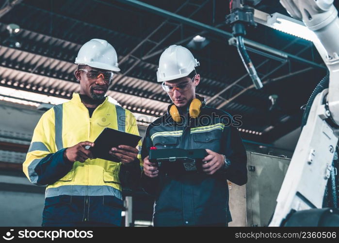 Factory workers working with adept robotic arm in a workshop . Industry robot programming software for automated manufacturing technology .. Factory workers working with adept robotic arm in a workshop