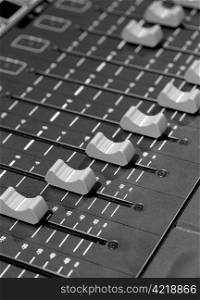 Faders of a studio soundboard. Black and white image scanned from medium format film. Film grain visible.