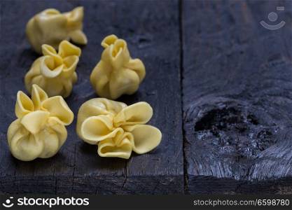 Fagottini pasta on dark rustic wood.. Fagottini pasta on dark rustic wood