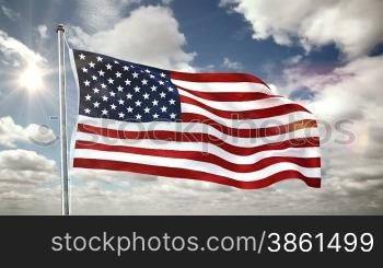 Fahne der USA weht im Wind. Darnber vorbeiziehende Wolken am Himmel bei strahlender Sonne.