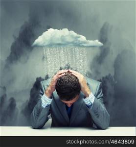 Failure in business. Depressed young businessman sitting wet under rain