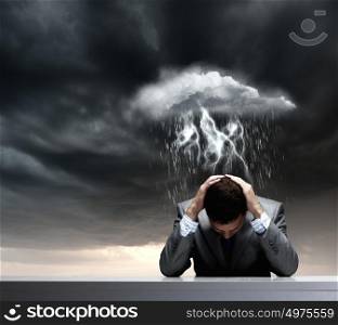 Failure in business. Depressed young businessman sitting wet under rain