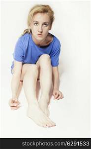 Fair-haired beautiful woman in blue shirt sitting on floor