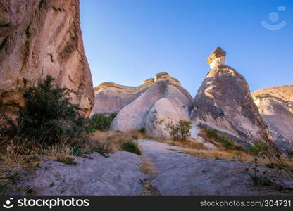 Fairy tale chimneys in Cappadocia, tourist attraction places to fly with hot air balloons. Goreme, Cappadocia, Turkey. Fairy tale chimneys in Cappadocia on the background of blue sky in Turkey.The great tourist attraction of Cappadocia one of the best places to fly with hot air balloons. Goreme, Cappadocia, Turkey