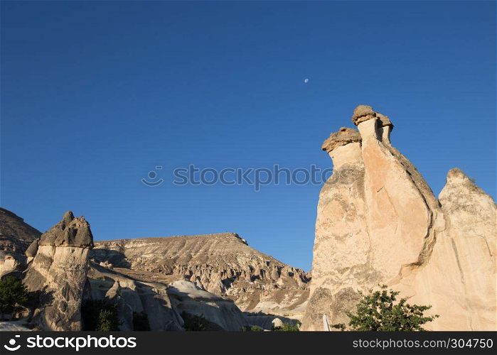Fairy tale chimneys in Cappadocia, tourist attraction places to fly with hot air balloons. Goreme, Cappadocia, Turkey. Fairy tale chimneys in Cappadocia on the background of blue sky in Turkey.The great tourist attraction of Cappadocia one of the best places to fly with hot air balloons. Goreme, Cappadocia, Turkey