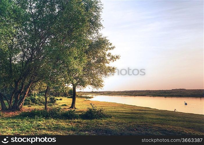 Fairytale style image of forest scene with lake and trees during vibrant sunset