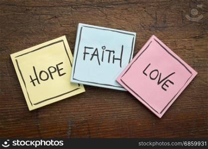 faith, love and hope - colorful sticky notes on rustic wood