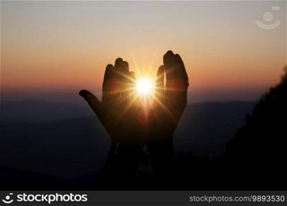 Faith of christian concept  Spiritual prayer hands over sun shine with blurred beautiful sunset background