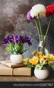 fake flowers different type vase with wrapped gift boxes against grunge background