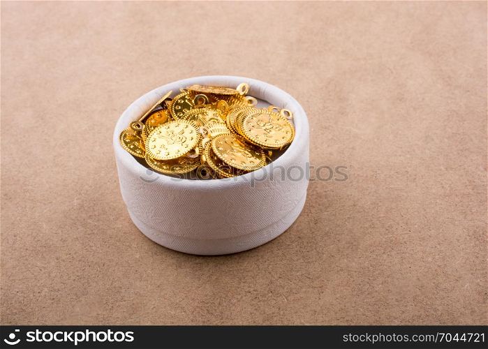 Fake gold coins in white box on brown background