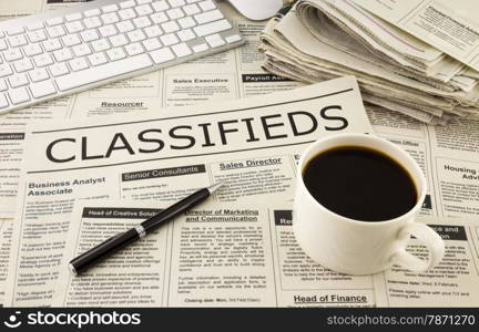 fake newspaper display classifieds advertising place on table with keyboard, pen and a cup of coffee