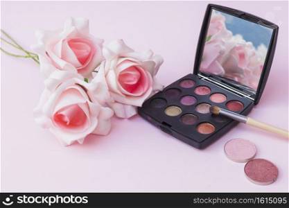 fake pink flowers with blusher eyeshadow palette with makeup brush