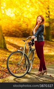Fall active lifestyle concept,. Beauty young redhaired woman fashion girl relaxing in autumn park with bicycle, outdoor