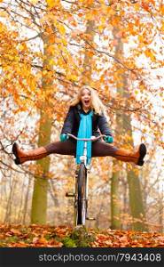 Fall active lifestyle concept. Happy crazy woman girl vivid color shawl relaxing in autumn park riding bicycle with her legs in the air having fun
