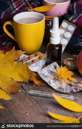 Fall and health care. cup of tea, pills and thermometer on a wooden background