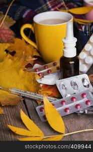 Fall and health care. cup of tea, pills and thermometer on a wooden background