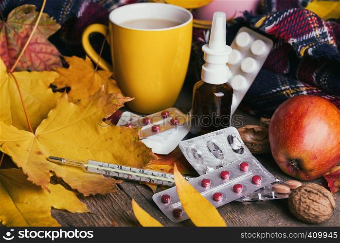 Fall and health care. cup of tea, pills and thermometer on a wooden background