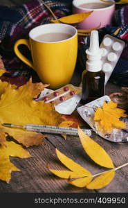 Fall and health care. cup of tea, pills and thermometer on a wooden background