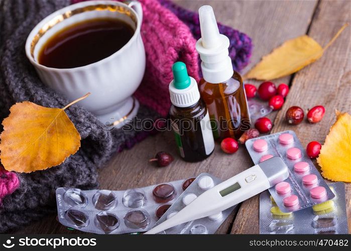 Fall and health care. home pharmacy - cup of tea, pills and thermometer on a wooden background